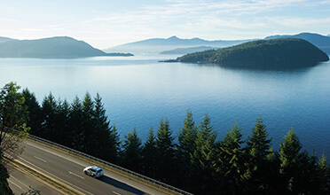 A car driving down a road next to the ocean