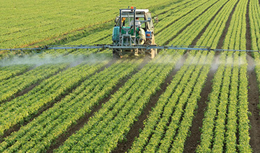 A tractor spraying pesticide on a field