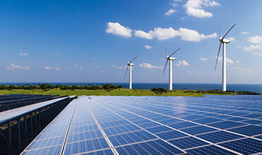 A row of wind turbines next to a row of solar panels